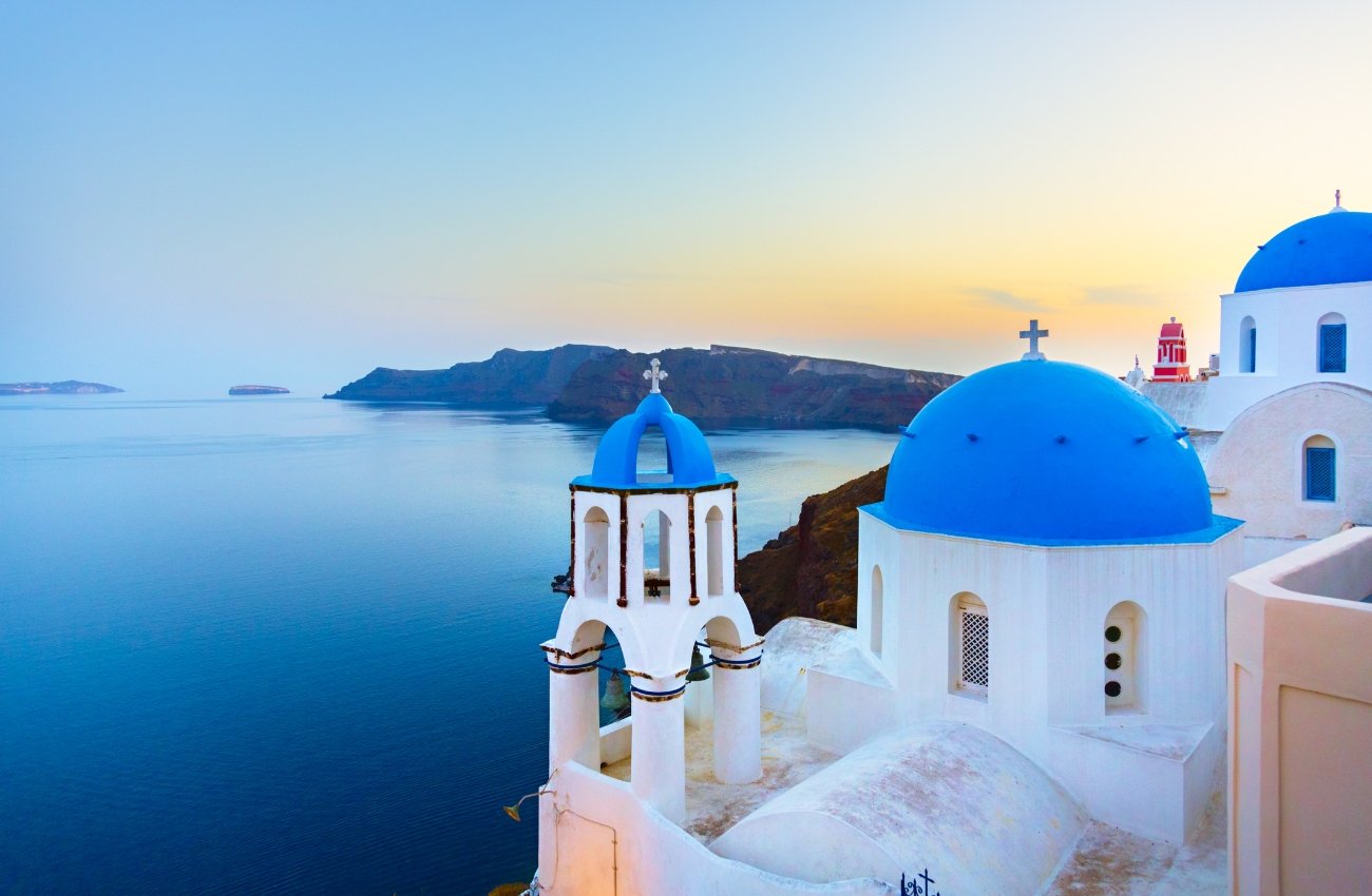 Greece's iconic blue domes in Santorini, create a stunning silhouette against the vibrant sunset.
